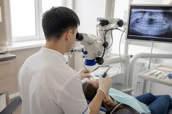 Chairside visit: dentist at work, over-the-shoulder shot of the assistant — illustration for the "Cysts and Neoplasms" section