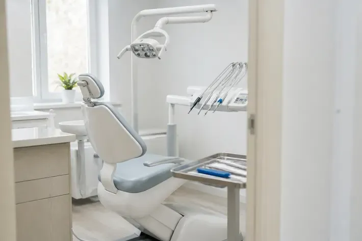 Treatment room prepared for an appointment: dental chair, lamp, and instrument tray — illustration for the section "Temporomandibular joints"
