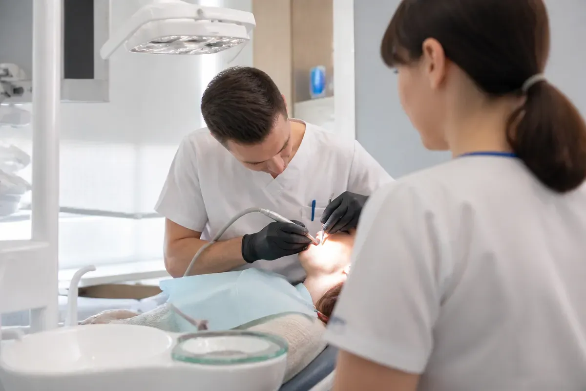 Chairside appointment: dentist at work, over-the-shoulder view of the assistant — illustration for the section "Zirconia framework crowns"