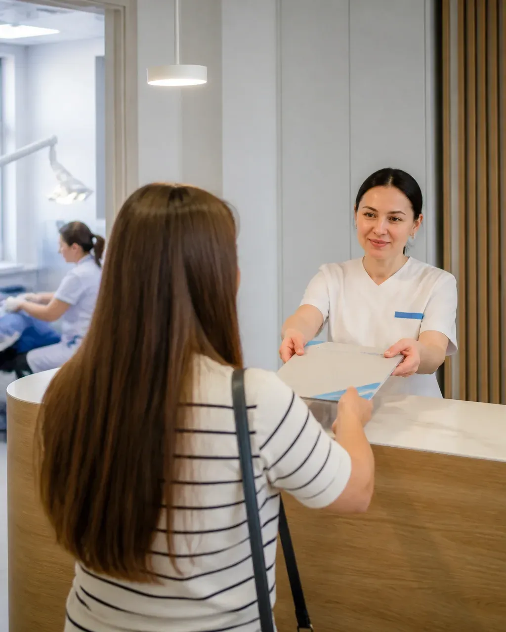 The clinic administrator gives the patient a treatment plan at the front desk