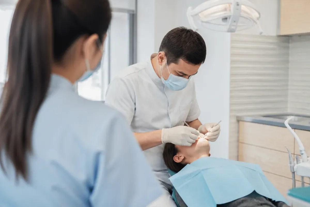 Chairside appointment: dentist at work, shot over the assistant's shoulder — illustration for the "Damon Systems" section