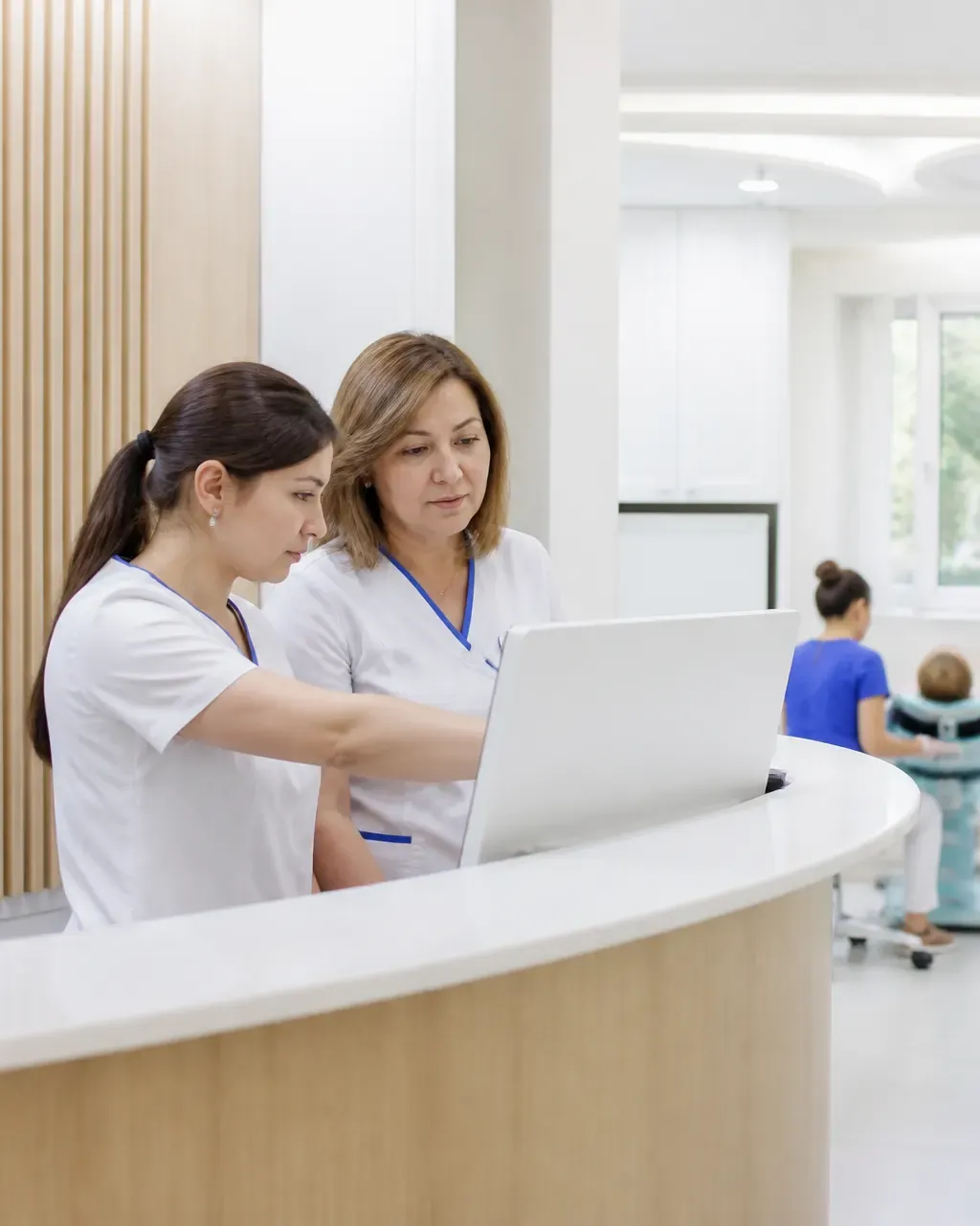 Clinic administrators check the appointment schedule on the screen at the front desk