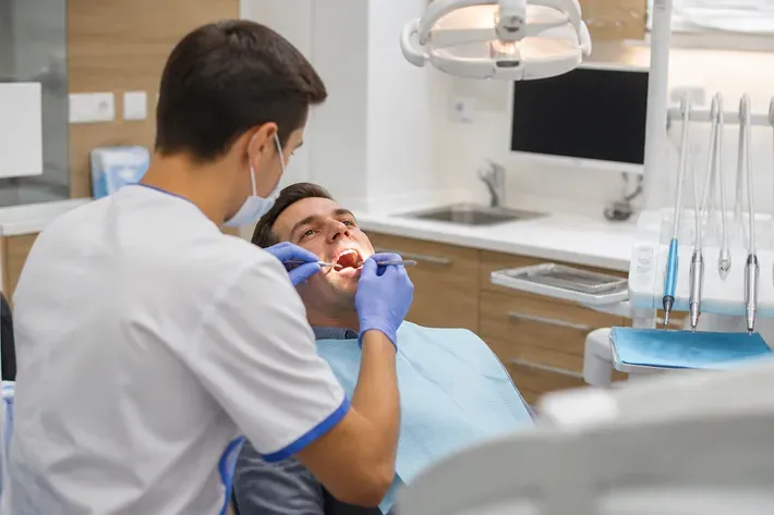Chairside appointment: dentist at work, over-the-shoulder view of the assistant — illustration for the "Service life" section