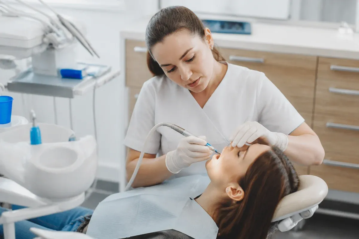 Chairside appointment: dentist at work, over-the-shoulder view of the assistant — illustration for the section "Erythritol-based powder"