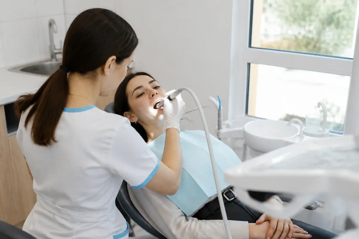Chairside appointment: dentist at work, over-the-shoulder shot past the assistant — illustration for the "Air Flow" section