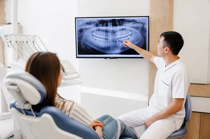 The doctor shows the patient the scan on the screen and explains the treatment plan — an illustration for the section "Retainer plate to maintain the result"