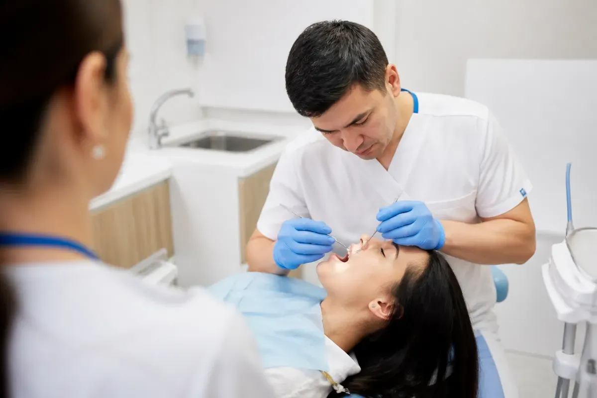 Chairside appointment: dentist at work, over-the-shoulder shot of the assistant — illustration for the section "What are the contraindications and possible side effects"