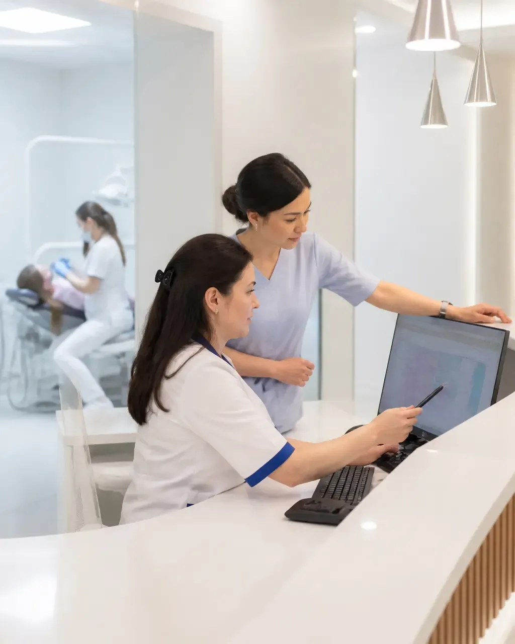Clinic administrators check the appointment schedule on the screen at the front desk