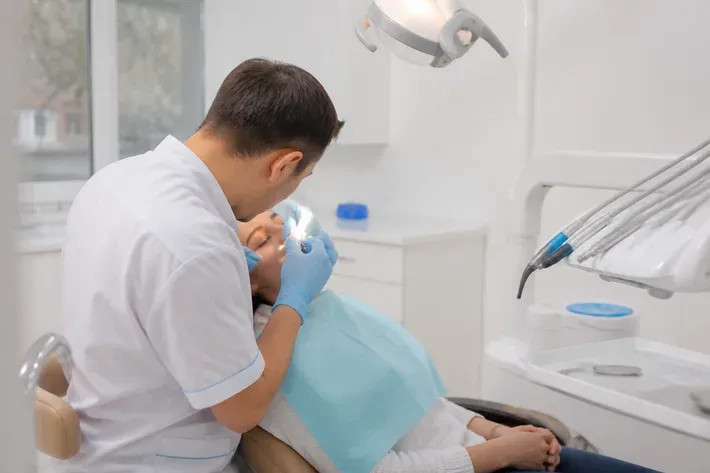 Chairside view: dentist at work, shot over the assistant's shoulder — illustration for the section "Which implants can be placed without surgery"