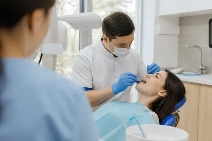 Chairside appointment: dentist at work, over-the-shoulder shot of the assistant — illustration for the "Short implants" section