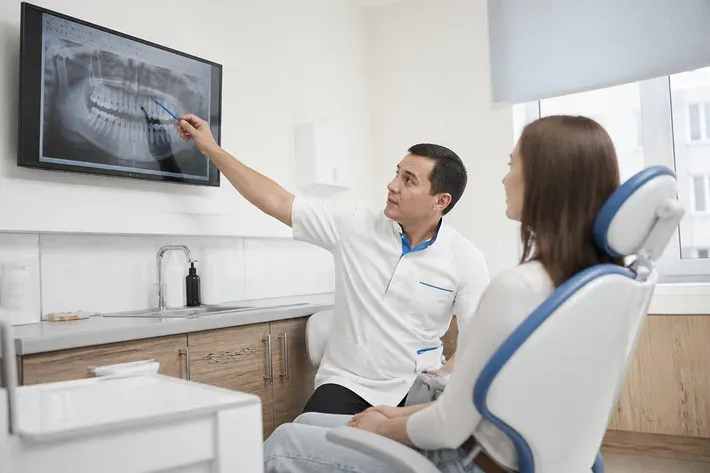 The doctor shows the patient an image on the screen and explains the treatment plan — an illustration for the section "What is included in the turnkey price"