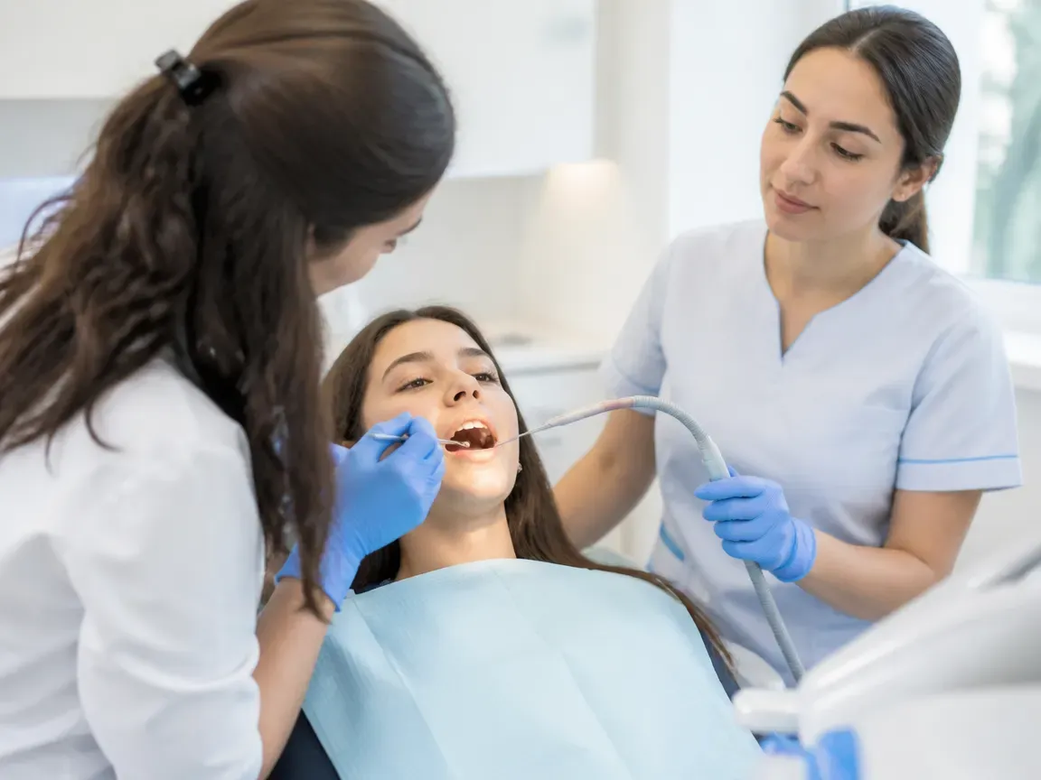 Follow-up visit: the doctor checks the result with a mirror while the assistant holds the saliva ejector — illustration for the section "Removal of the system and retention period"
