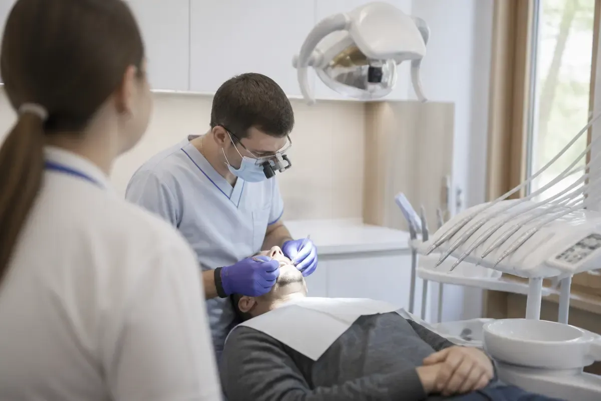 Chairside appointment: dentist at work, shot over the assistant's shoulder — illustration for the "MIS C1" section