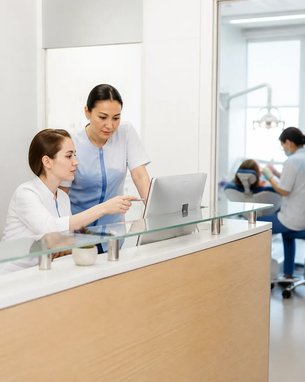 Clinic administrators check the appointment schedule on the screen at the front desk