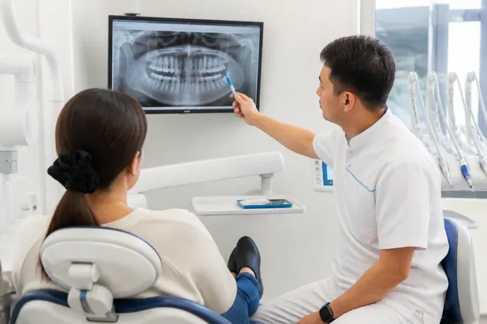 The doctor shows the patient an image on the screen and explains the treatment plan — an illustration for the section "Korean Osstem implants: what you need to know"