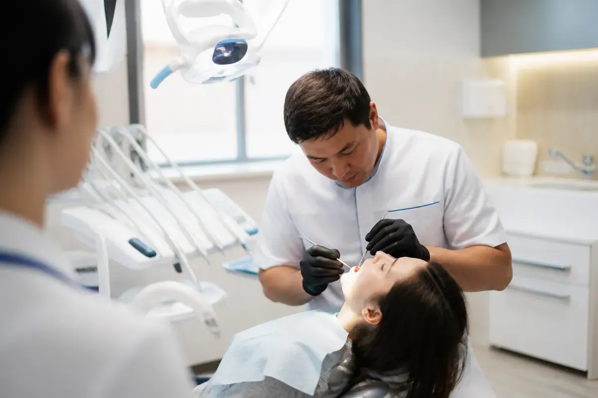 Chairside appointment: dentist at work, shot over the assistant's shoulder — illustration for the "Who places" section