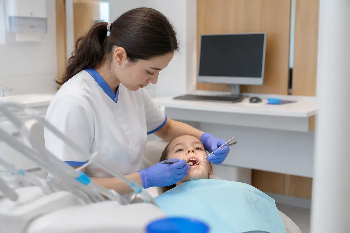 Chairside appointment: dentist at work, over-the-shoulder shot of the assistant — illustration for the section "Safe Materials for Pediatric Crowns"