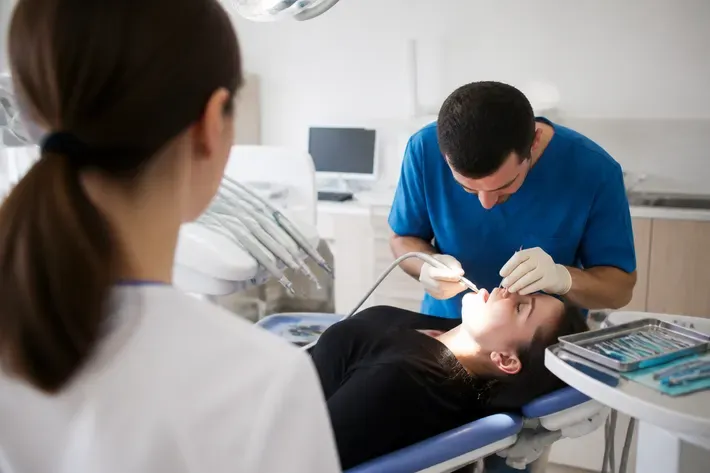 Chairside appointment: dentist at work, shot over the assistant's shoulder — illustration for the section "Xenograft material"