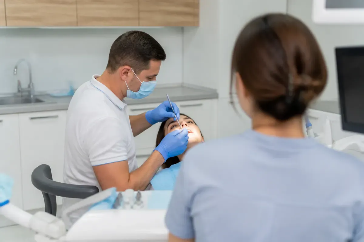 Chairside appointment: dentist at work, over-the-shoulder view of the assistant — illustration for the "Surgical Treatment" section