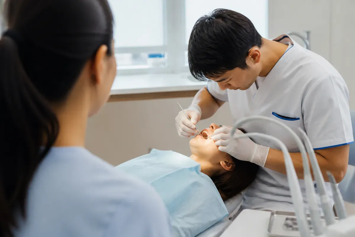 Chairside appointment: dentist at work, over-the-shoulder shot of the assistant — illustration for the section "Treatment methods for exposed tooth necks"