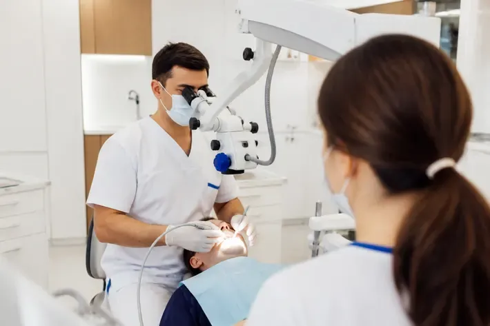 Chairside appointment: dentist at work, over-the-shoulder view of the assistant — illustration for the section "Chronic periodontitis"