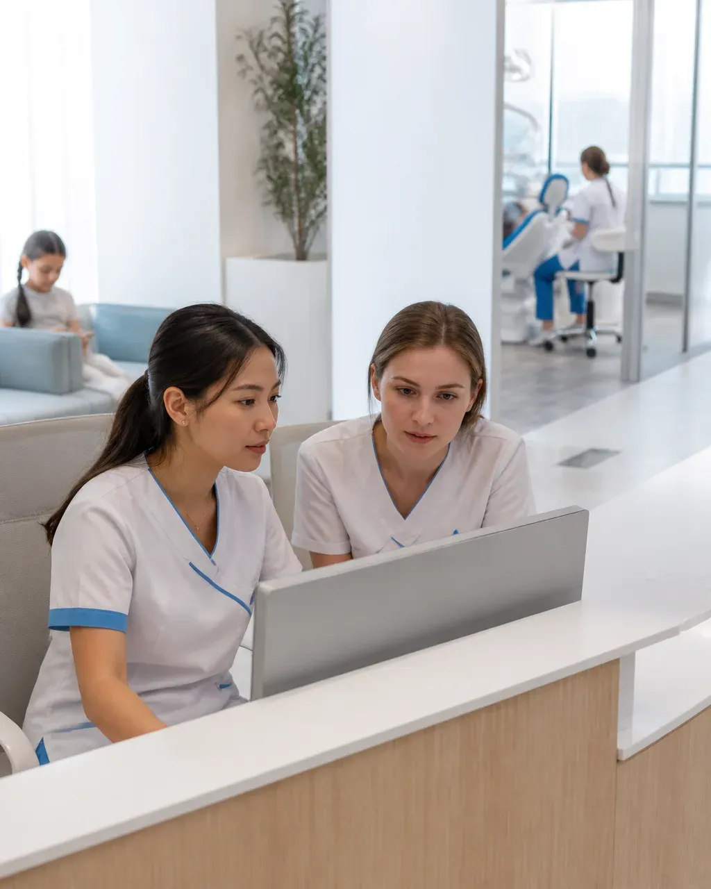 Clinic administrators check the appointment schedule on the screen at the front desk