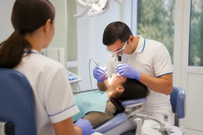 Chairside care: dentist at work, over-the-shoulder view of the assistant — illustration for the "Sedation" section