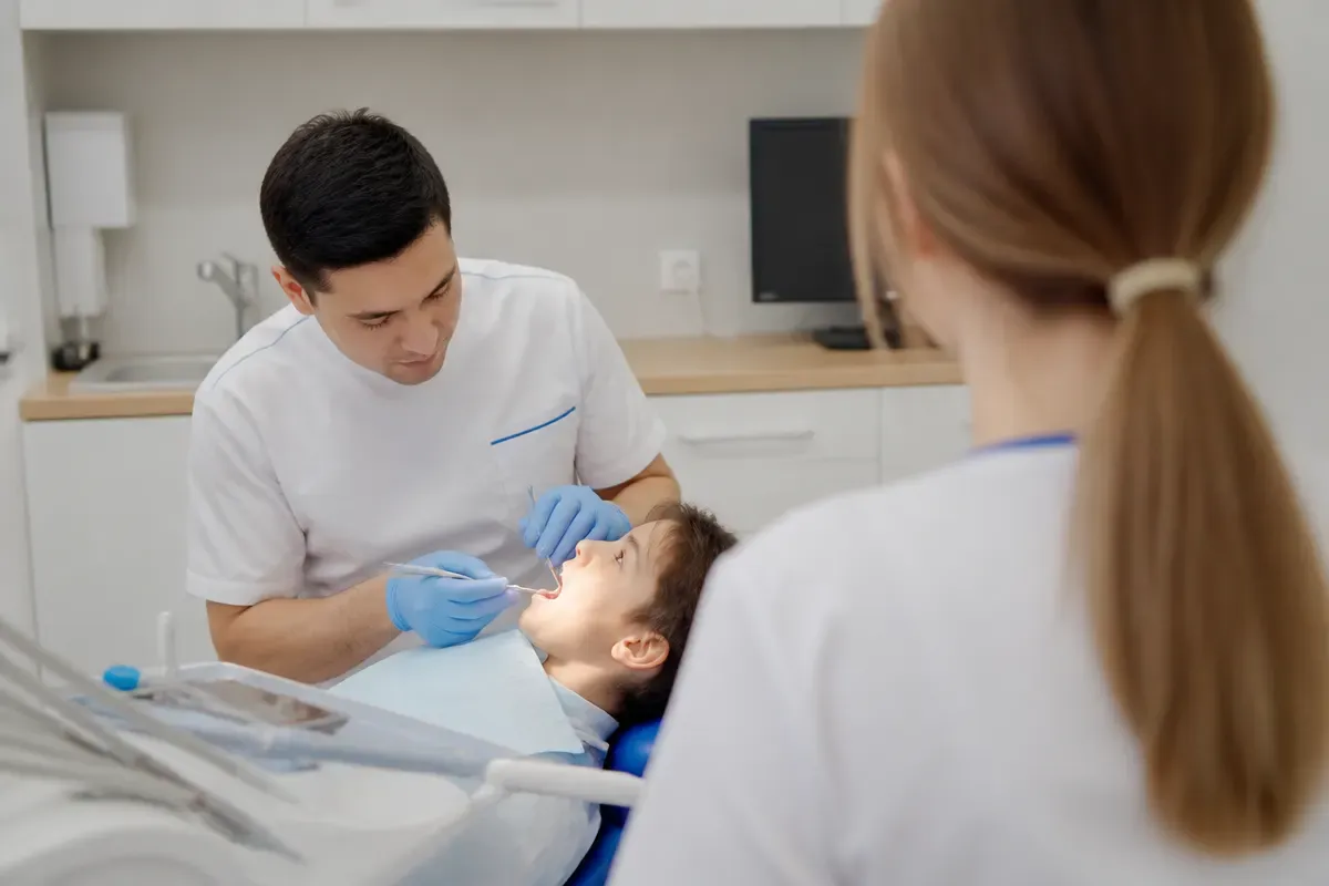 Chairside appointment: dentist at work, over-the-shoulder shot of the assistant — illustration for the section "Which teeth and which conditions are treated under sedation"