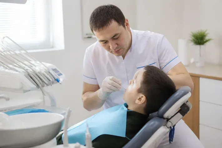 Chairside appointment: dentist at work, shot over the assistant's shoulder — illustration for the "Pediatric Surgeon" section