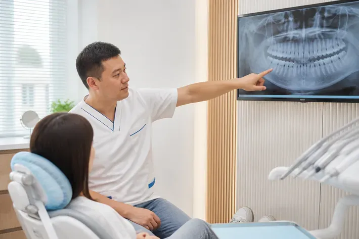 The doctor shows the patient an image on the screen and explains the treatment plan — an illustration for the section "Who is a suitable candidate for the Damon Q metal bracket system"