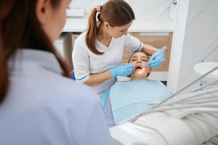 Chairside appointment: dentist at work, over-the-shoulder view of the assistant — illustration for the section "Open bite and crossbite"