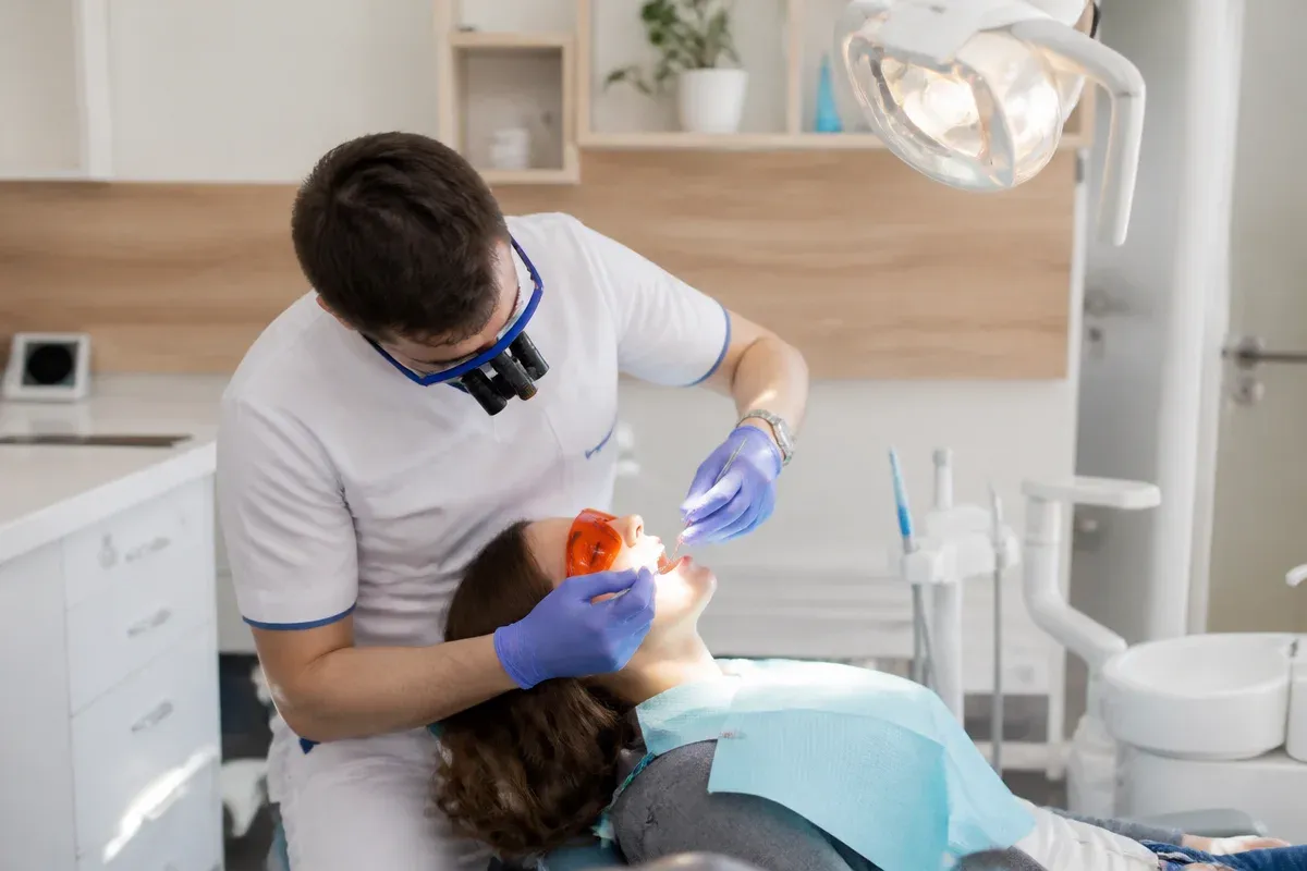 Chairside appointment: dentist at work, over-the-shoulder shot of the assistant — illustration for the section "How the system works: the enamel whitening mechanism"