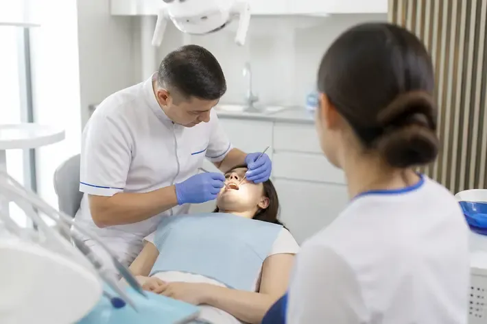 Chairside appointment: dentist at work, over-the-shoulder shot of the assistant — illustration for the section "Removable lower denture"