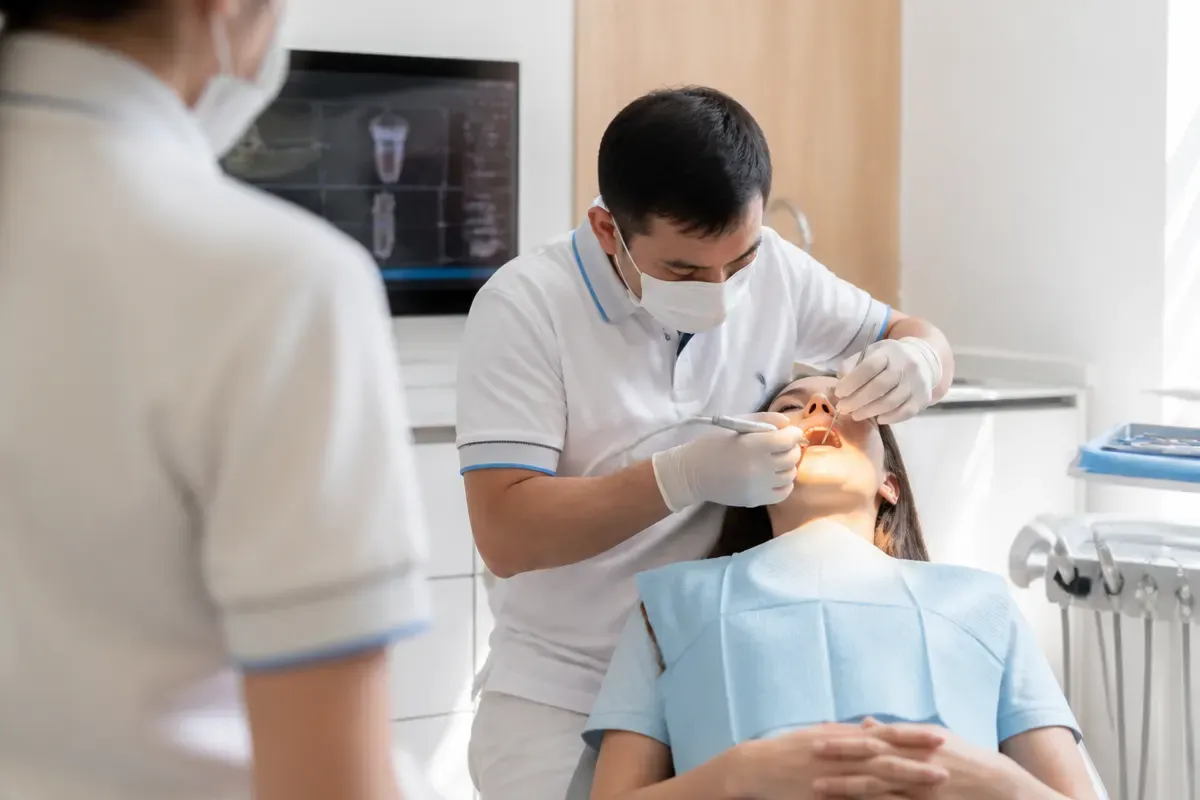 Chairside appointment: dentist at work, over-the-shoulder shot past the assistant — illustration for the "Side effects" section