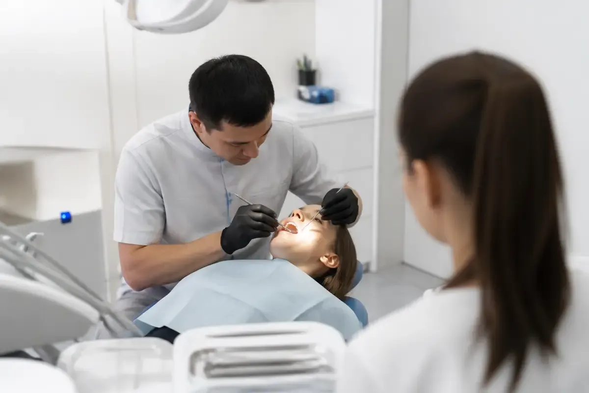 Chairside appointment: dentist at work, over-the-shoulder view of the assistant — illustration for the section "Indications in adults and children"
