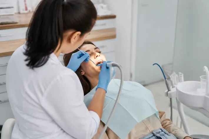 Chairside appointment: dentist at work, over-the-shoulder shot past the assistant — illustration for the "Air Flow" section