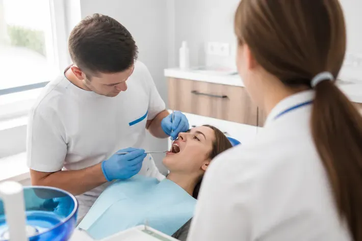 Chairside appointment: dentist at work, over-the-shoulder shot of the assistant — illustration for the "Nylon" section