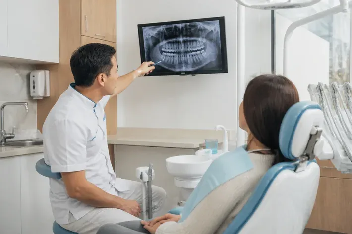 The doctor shows the patient an image on the screen and explains the treatment plan — an illustration for the section "What complications can occur after prosthetics"