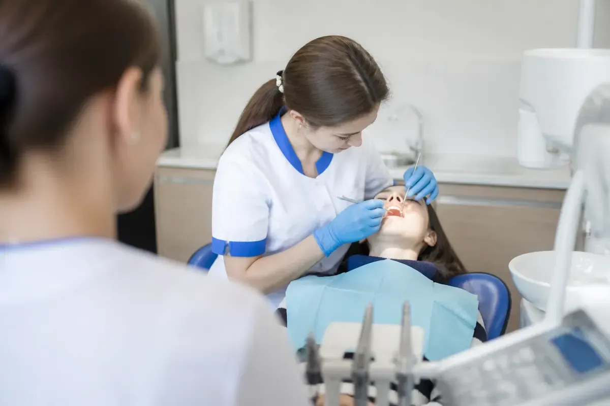 Chairside appointment: dentist at work, over-the-shoulder shot of the assistant — illustration for the "Fluoridation" section
