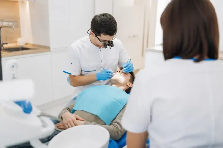Chairside appointment: dentist at work, over-the-shoulder shot of the assistant — illustration for the section "Panoramic radiograph of both jaws"