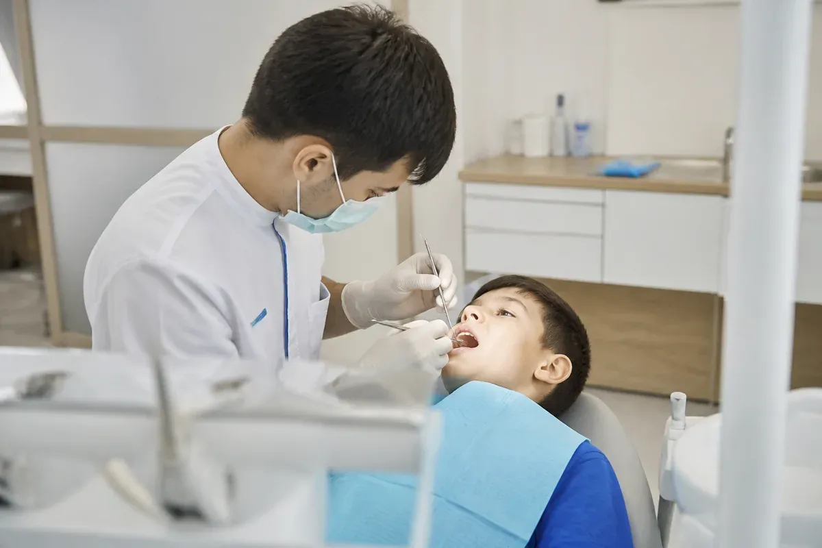 Chairside appointment: dentist at work, shot over the assistant's shoulder — illustration for the section "What types of dental X-rays exist: periapical, panoramic, CT — how they differ and when they are needed"