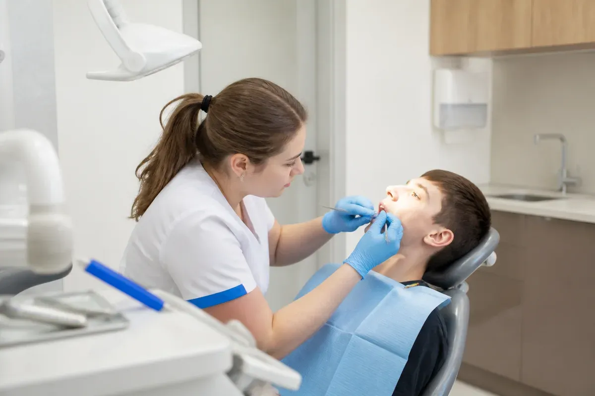 Chairside appointment: dentist at work, over-the-shoulder view of the assistant — illustration for the "Removable Retainer" section