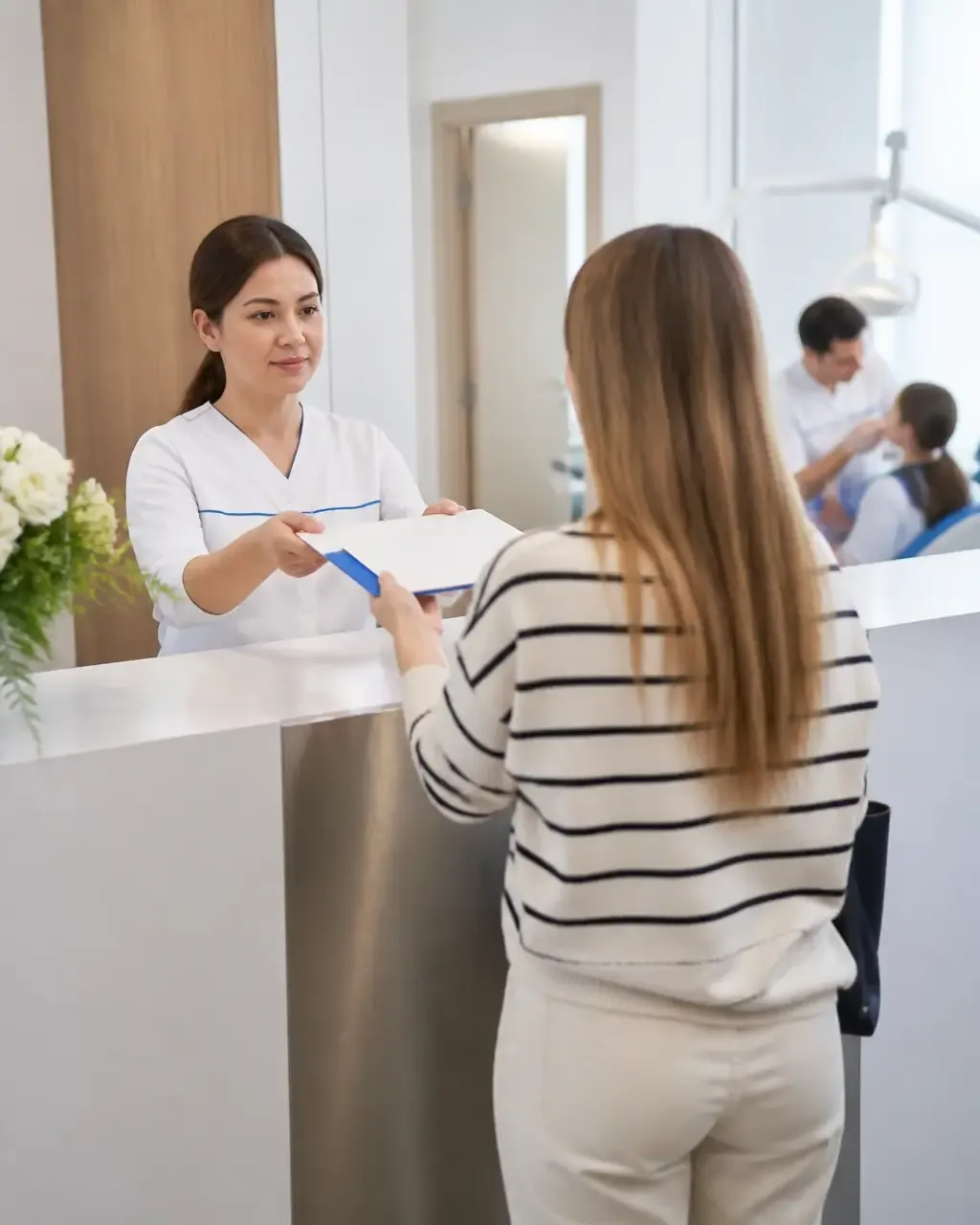 The clinic administrator gives the patient a treatment plan at the front desk