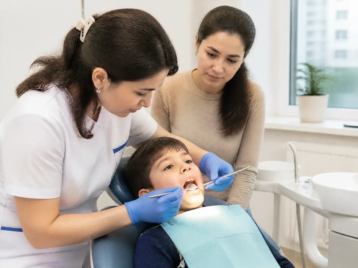 silver diamine fluoride application on primary teeth — dentist showing the patient a treatment plan on screen in a bright office