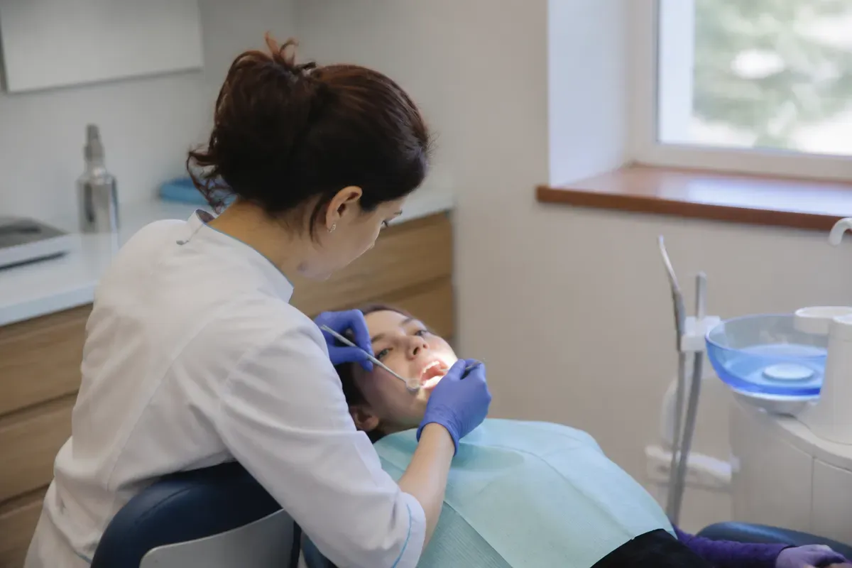 Chairside appointment: dentist at work, over-the-shoulder shot of the assistant — illustration for the section "Complications after silver diamine fluoride application"