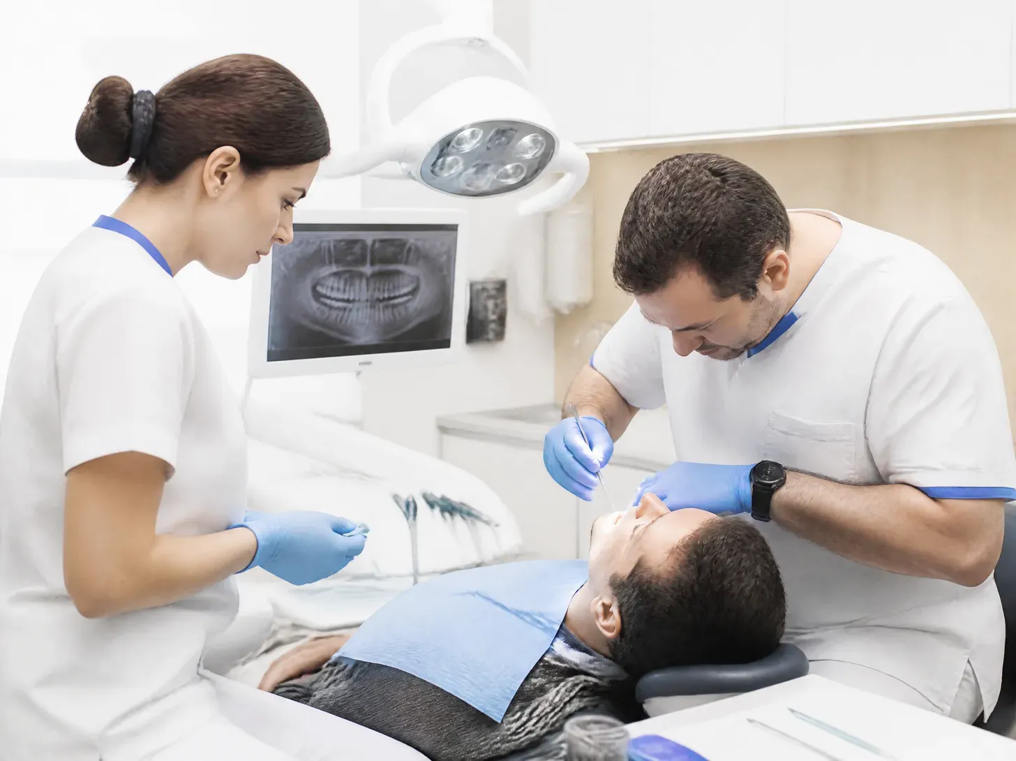 dental surgery — dentist showing a patient a treatment plan on a screen in a bright office