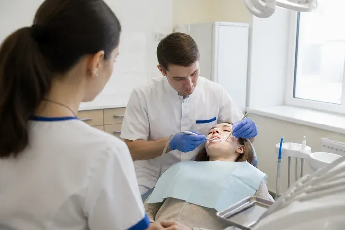 Chairside appointment: dentist at work, over-the-shoulder shot of the assistant — illustration for the "Materials and Limitations" section