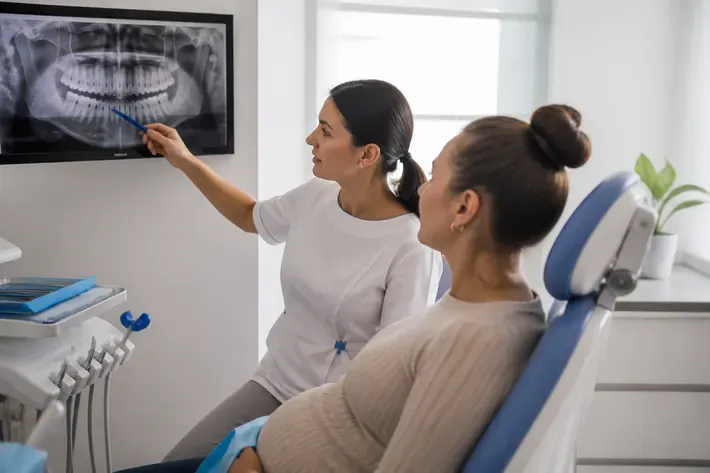 Doctor showing a patient an X-ray on screen and explaining the treatment plan — illustration for the "Treatment Warranty" section