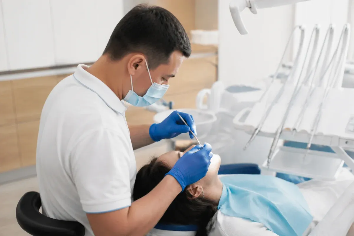 Chairside appointment: dentist at work, over-the-shoulder view of the assistant — illustration for the section "Which denture is best when all teeth are missing"