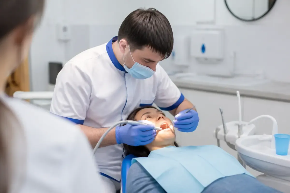 Chairside appointment: dentist at work, over-the-shoulder shot past the assistant — illustration for the "Complex Extraction" section